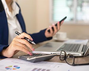 woman's hands holding pen and calculator mid-work plan