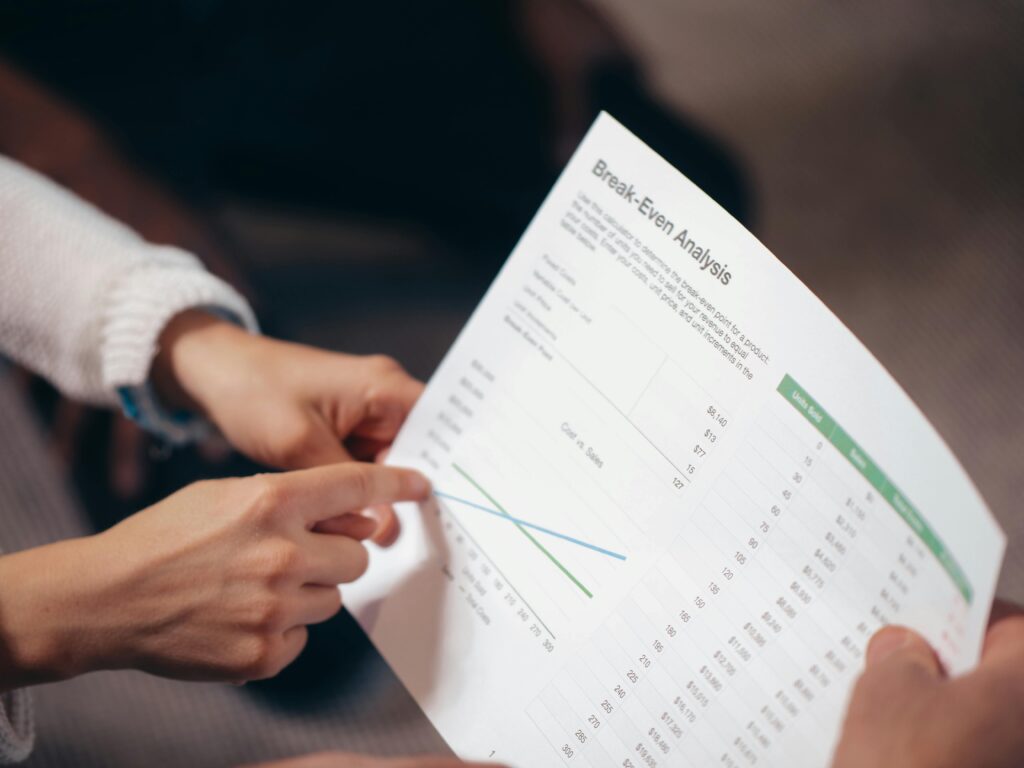 people pointing at sheet of paper displaying data
